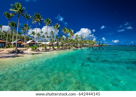 Tropical beach with with coconut palm trees and villas on Samoa Island