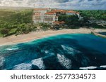 Tropical beach with luxury hotel, ocean and waves in Bali island. Aerial drone shot