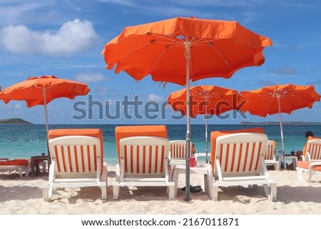tropical beach with orange umbrellas and beach chairs in Orient Bay, Saint Martin island