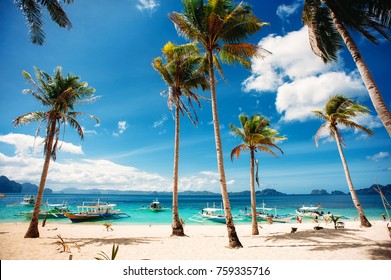 Tropical beach with palm trees, pilippine boats, blue sky, turquoise water and white sand. Paradise. Philippines, Palawan, El Nido. Wide angle, horizontal