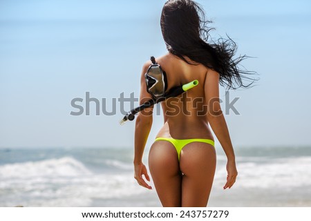 Tropical beach postcard. Beautiful brunette girl back with snorkeling stuff