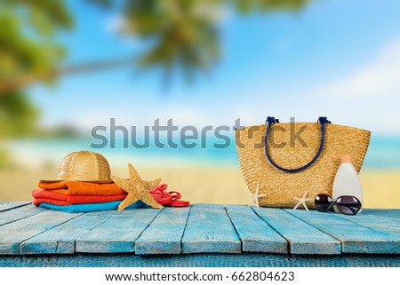 Tropical beach with sunbathing accessories placed on blue wooden planks, summer holiday background. Travel and beach vacation, free space for text.