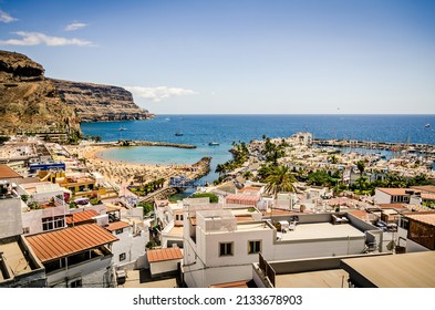 Tropical Beach Town With Harbour, Turquoise Sea, Traditional Houses And Cliffs. Summer Holiday Vibe. Tourist Spot. Puerto De Mogan, Canary Islands Spain