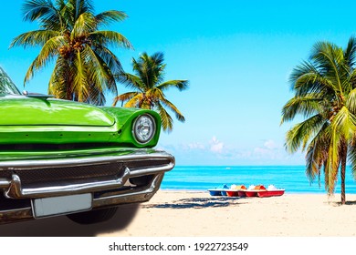 The tropical beach of Varadero in Cuba with green american classic car, sailboats and palm trees on a summer day with turquoise water. Vacation background