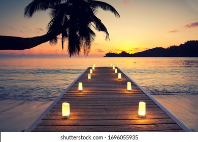 tropical beach with wooden jetty and candles, Indian Ocean at sunset. Holidays destination