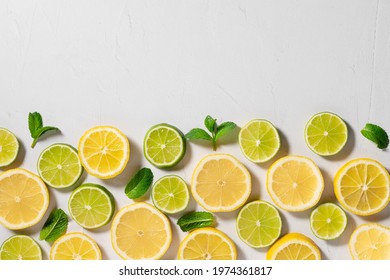 Tropical Citrus Background. Slices Of Lemon, Lime And Mint Leaves On White Background. Summer Food Border. Flat Lay. Copy Space
