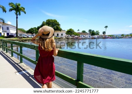 Tropical destination. Happy woman with hat walking relaxed on bridge looking away. Summer vacation concept.
