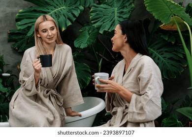 Tropical and exotic spa garden with bathtub in modern hotel or resort with young two women in bathrobe drink coffee, enjoy leisure and wellness lifestyle surround by lush greenery foliage. Blithe - Shutterstock ID 2393897107
