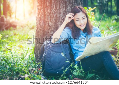 In tropical forest. Asian girls hikers She is holding a map and analysis of travel plans within the forest amid the hot weather and afternoon sun with copy space.