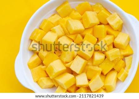 Tropical fruit, Mango cube slices in white bowl on yellow background.