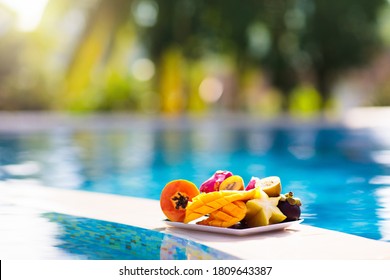 Tropical fruit plate at swimming pool. Mango, pineapple, orange and fresh juice on summer vacation at exotic island. Healthy nutrition. Beach holiday and swim fun. - Powered by Shutterstock