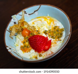 Tropical Fruity Mousse Dessert From Maracuya Pulp With Cream Garnished With Chocolate Flakes, Strawberry And Physalis