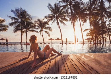 tropische Unterkunft im Luxushotel am Strand, luxuriöse Reise, Frau, die sich bei Sonnenuntergang in der Nähe des Swimmingpools entspannt