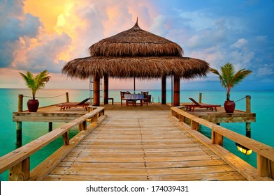 Tropical hut on water at sunset - romantic dinner in paradise - Powered by Shutterstock