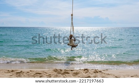 Tropical Island Koh Kood A tropical beach paradise with a beach swing. Women relax on a swing under a coconut palm tree at a beautiful tropical beach White sand holiday summer vacation