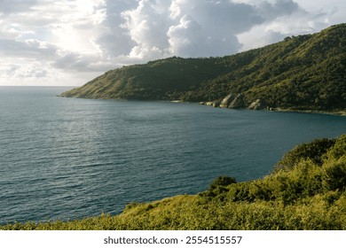 A tropical island with lush greenery, a rocky coastline, and azure waters under a cloudy sky. This picturesque natural landscape captures the essence of tranquility, seclusion, and tropical exoticism - Powered by Shutterstock