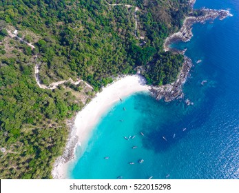 Tropical island with white sand beach and turquoise clear water, longtail boats and granite stones. Top view. Aerial shooting of Freedom beach, Phuket, Thailand.