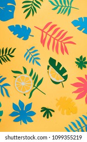 Tropical leaves and fruits pattern on a bright yellow background. Sunny summer colorful flat lay with paper cut outs.