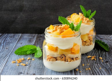 Tropical mango and pineapple parfaits in mason jars, scene on dark rustic background - Powered by Shutterstock