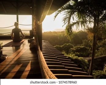 tropical open yoga studio place with people and a view outside to the ocean while sunset
