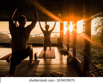 tropical open yoga studio place with people and a view outside to the ocean while sunset
