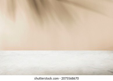 Tropical palm tree shadow on cream wall and luxury marble table for product placement. Natural layout design background. Abstract summer light cosmetic stand mockup.
