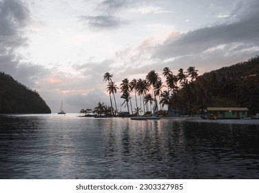 Tropical sandy beach with palm trees in turquoise lagoon in the Caribbean Islands, sailboats anchoring in Marigot Bay of St Lucia, traveling into exotic destination, yachting lifestyle