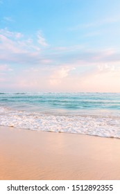 Tropical shore. Sandy beach, blue cloudy sky and soft ocean wave in evening warm sunlight.