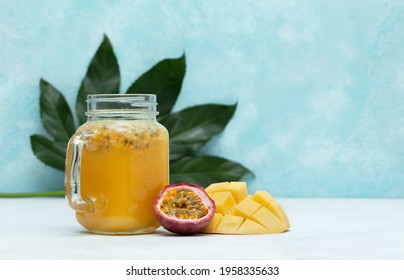 tropical smoothie mango and passionfruit in a jar mason, fresh mango and passionfruit on a blue background - Shutterstock ID 1958335633