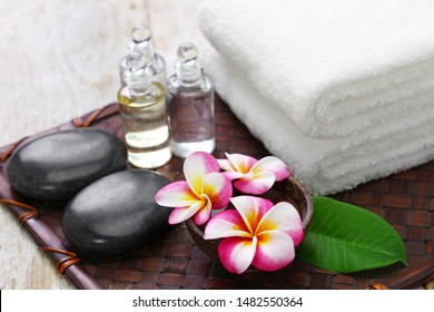 tropical spa resort concept; plumeria, hot stones, towels, and massage oils