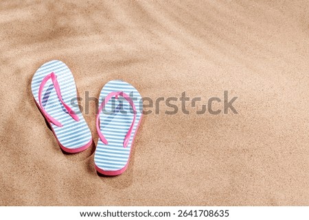 A tropical summer background featuring soft beach sand with delicate palm leaf shadows and a pair of colorful flip-flops, creating a warm and relaxing seaside atmosphere