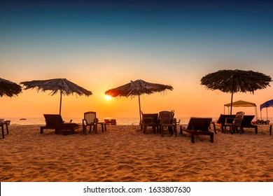 Tropical sunny beach party at Sunset with Sun umbrellas and lounge chairs in GOA, India	
