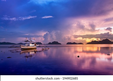 Tropical sunset with a banca boat in El Nido, Palawan - Philippines. 