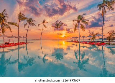 Tropical sunset over outdoor infinity pool in summer seaside resort, beach landscape. Luxury tranquil beach holiday, poolside reflection, relaxing chaise lounge romantic colorful sky, chairs umbrella - Shutterstock ID 2164993687