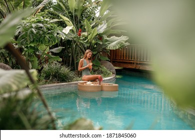 Tropical Travel Lifestyle, Vacation On Bali Island. Pretty Young Woman Enjoying Breakfast In The Swimming  Pool Diring Tropical Vacation