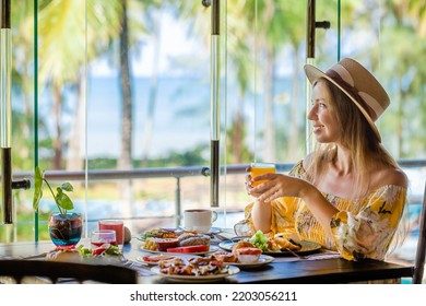 Tropical vacation. Breakfast in modern hotel resort with sea and palm trees on background. Traveler woman on summer holidays on Phuket, Thailand. Exotic travel in Southeast Asia