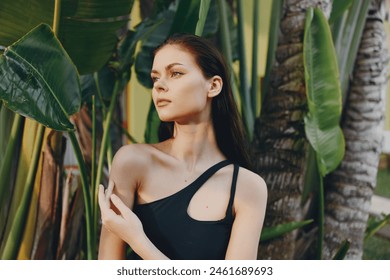 Tropical Vacation Vibes Woman in Black Swimsuit Standing Among Palm Trees at a Beach Resortvacation beach tropics joyful person swimsuit relaxation serene resort coastline cheerful travel holidays - Powered by Shutterstock