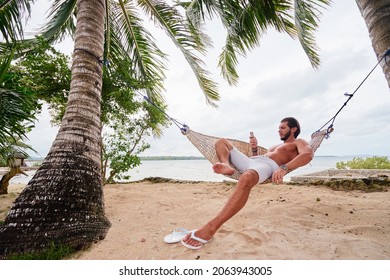 Tropical vacation. Young man relaxing at hammock on tropical beach. - Powered by Shutterstock