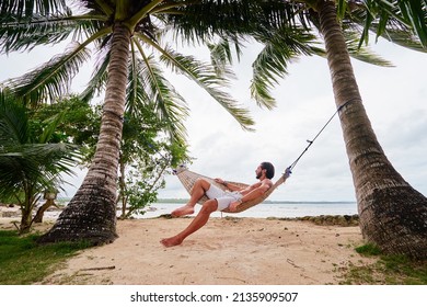 Tropical vacation. Young man relaxing at hammock on tropical beach. - Powered by Shutterstock