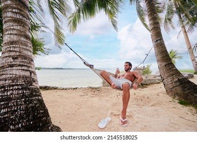 Tropical Vacation. Young Man Relaxing At Hammock On Tropical Beach.