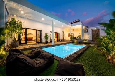 Tropical villa view with garden, swimming pool and open living room at sunset. - Powered by Shutterstock