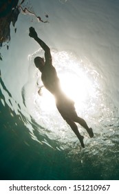 In The Tropical Western Pacific Ocean, A Swimmer Is Silhouetted By The Bright Sun.