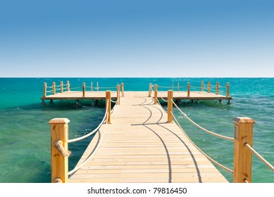 tropical wooden pier in turquoise sea at sunny weather, clear skies, empty