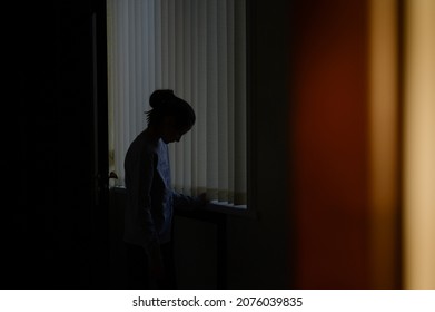 trouble and problem concept of domestic violence upset sad little girl on blue window background in sunset home room - Shutterstock ID 2076039835