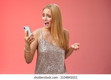 Troubled concerned arrogant young blond woman complaining yelling smartphone cannot call friend no signal holding smartphone look mobile display pissed moody arguging, red background