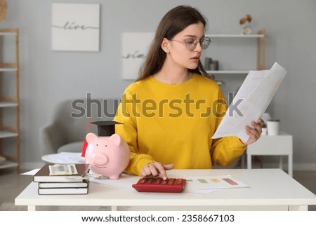 Troubled female student sitting at table and calculating her finances. Student loan concept