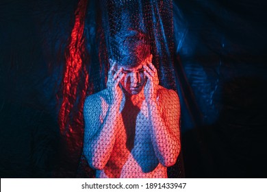 Troubled Man. Panic Attack. Emotional Crisis. Social Pressure. Art Portrait Of Paranoid Hurt Shirtless Guy Suffering From Headache In Mesh Trap In Red Blue Neon Light At Night On Dark Background.