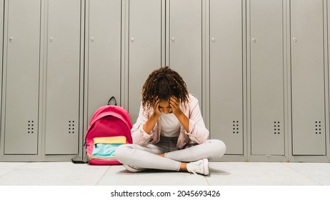 Troubles at school. Lonely sad african-american schoolgirl crying at school hall. Social exclusion problem. Bullying at school concept. Racism problem.Puberty difficult age - Powered by Shutterstock