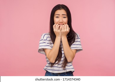 Troubles and worries. Portrait of nervous girl with long brunette hair biting nails and looking frightened, terrified about problems, suffering phobia, anxiety disorder. indoor studio shot isolated