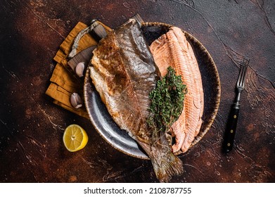 Trout roasted fillet, grilled fish on a plate with thyme and lemon. Dark background. Top view